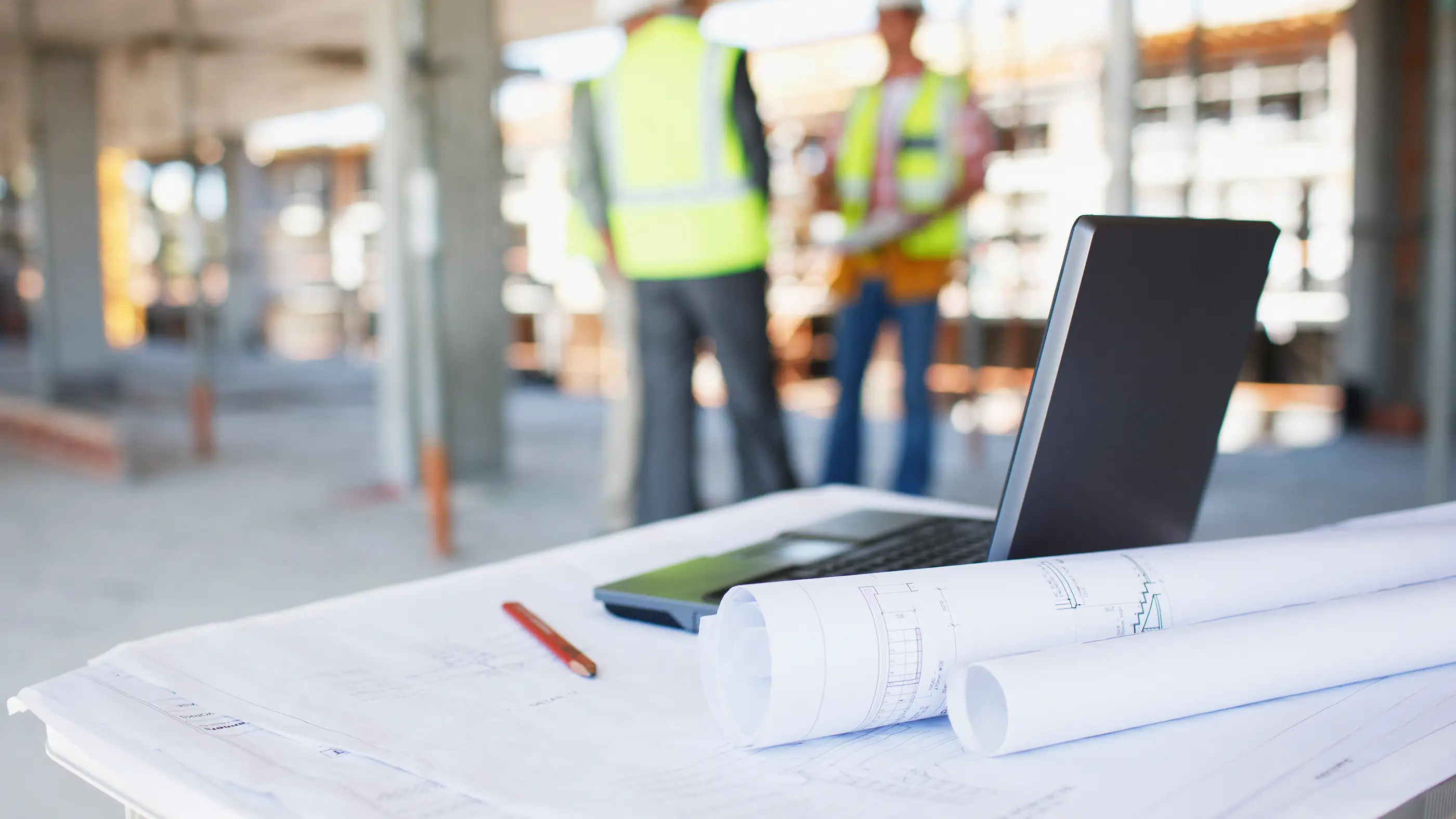 Architect on job site collaborating with team with drawings in the foreground
